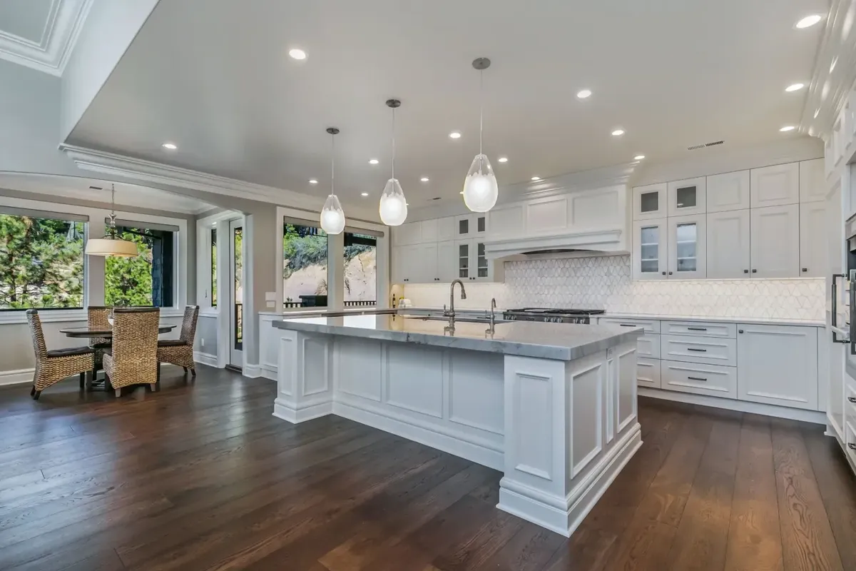 White kitchen with a big island and globe pendants by Bend Build & Remodel