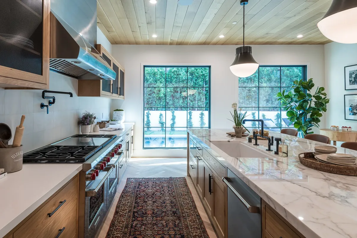 Kitchen with a wood ceiling, white counters and a pro range by Birchleaf Interiors