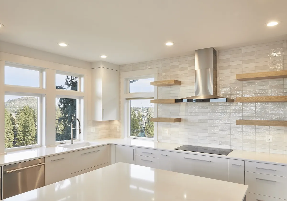 Bright white kitchen with a tile backsplash and vaulted ceiling by DCR Northwest