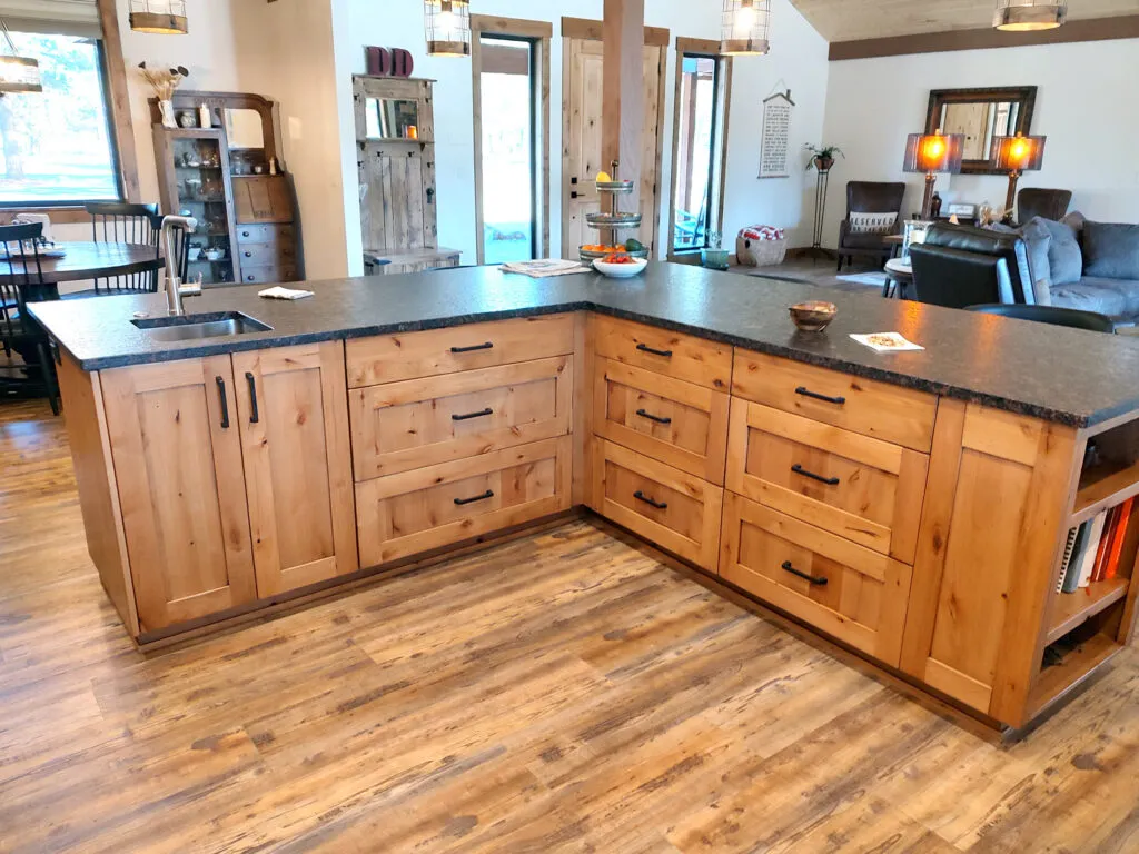 Knotty wood kitchen cabinets with dark counters by Deep Roots Construction in Sisters