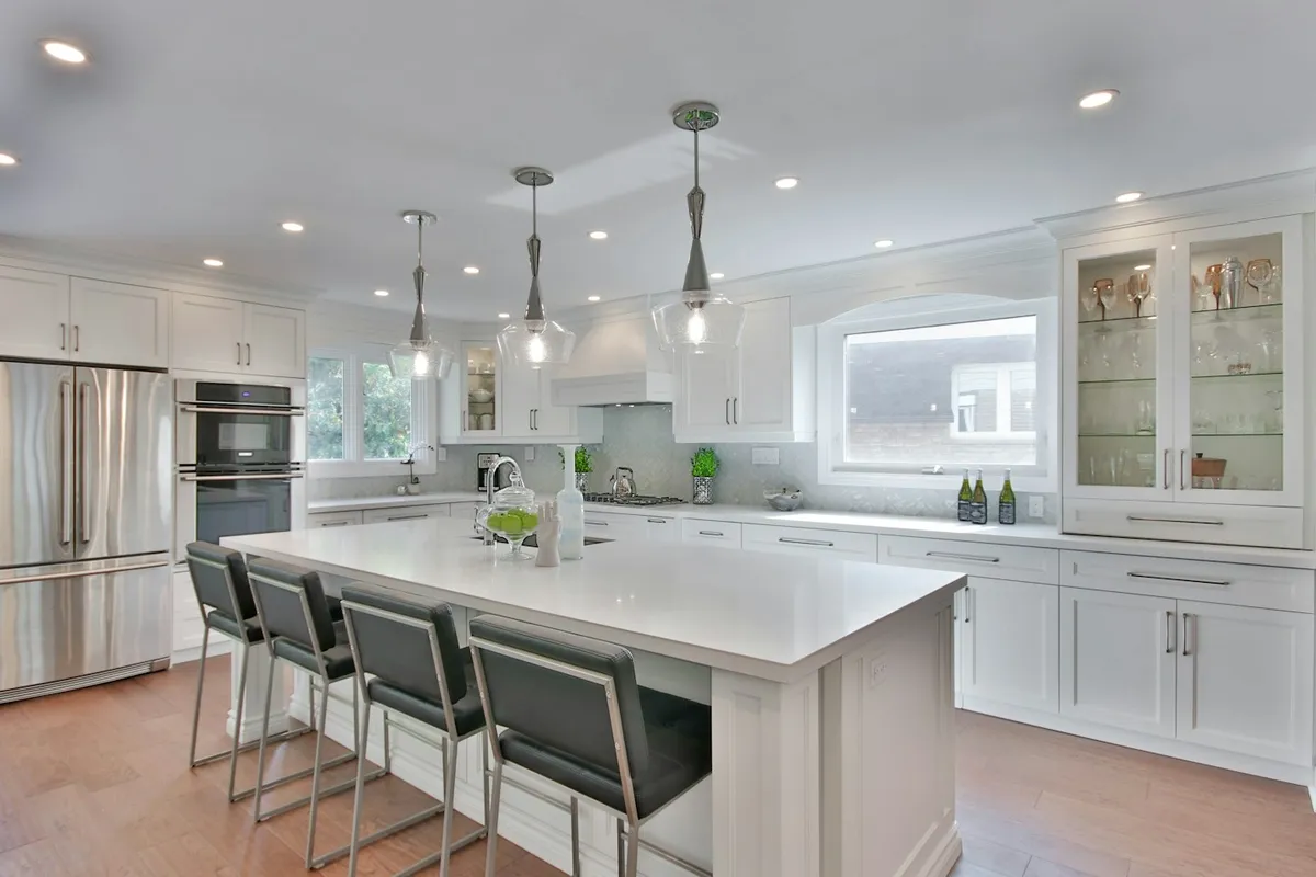 Bright kitchen with an island and pendant lights by Designer Baths & Kitchens