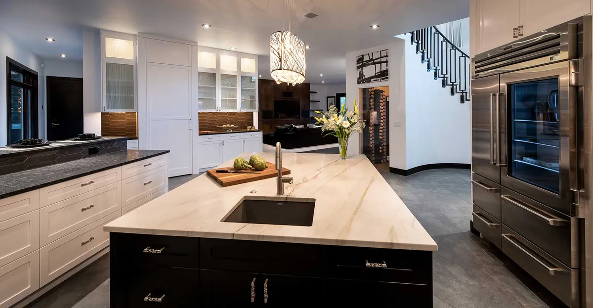 Modern kitchen with a white island and dark cabinets by DH Builders