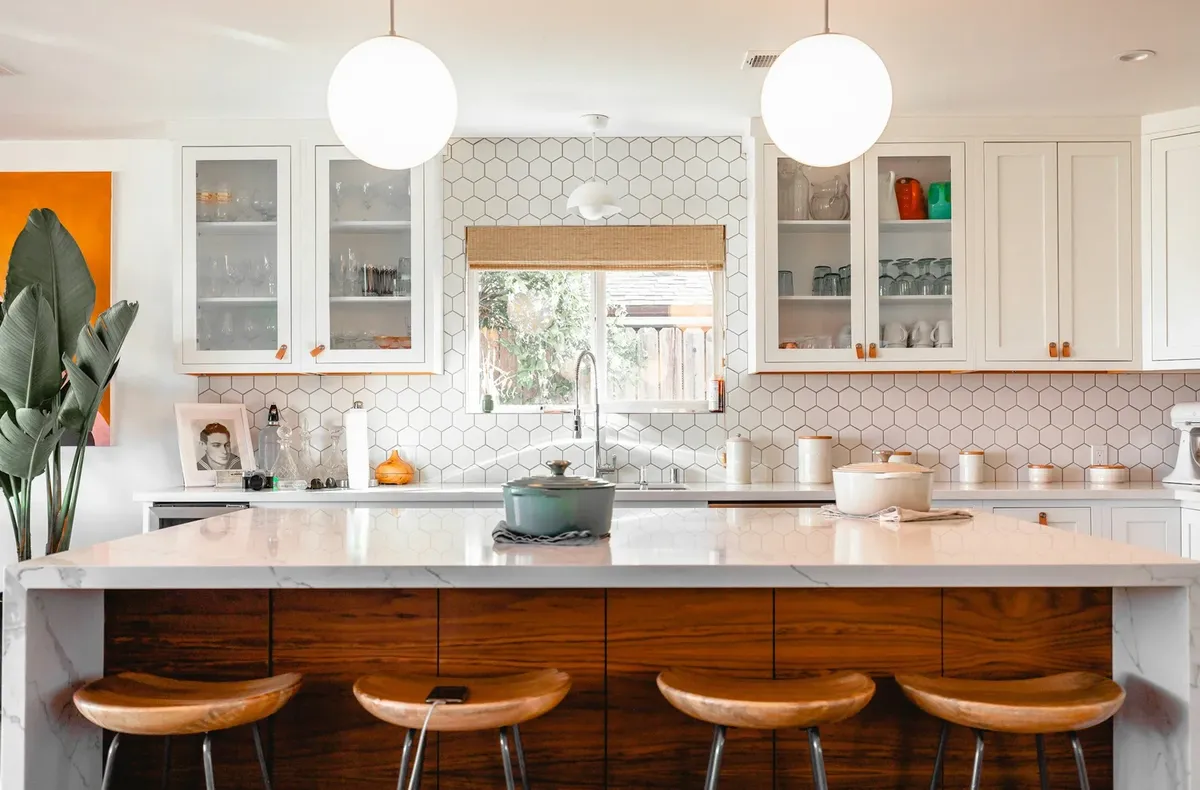 Kitchen with a long wood bar and white cabinets by S&K Remodeling