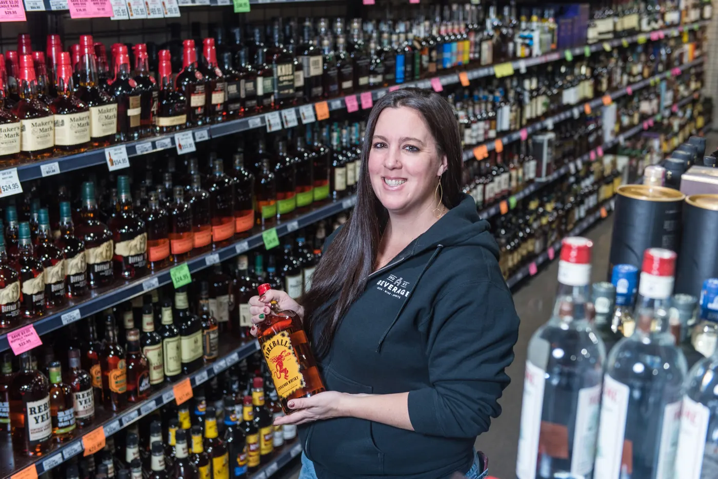 A staff member holding a bottle in the spirits aisle at 3rd Street Beverage in Bend
