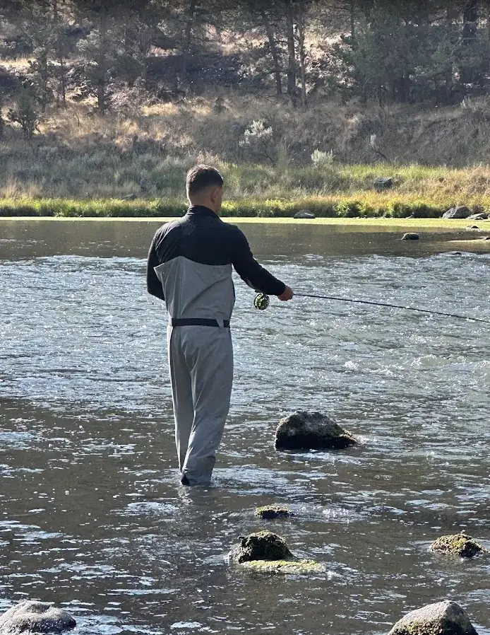 Angler in waders fly fishing a riffle on a Central Oregon river