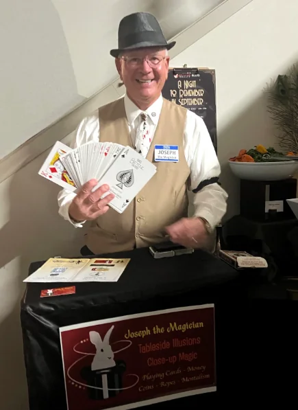 Joseph the Magician holding a fan of playing cards at his tableside magic station