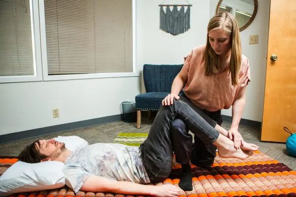 A Thai massage stretch on a floor mat at Spectrum Massage Therapy