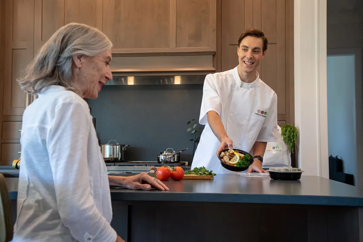 A personal chef serving a meal in a home kitchen, from Chefs for Seniors