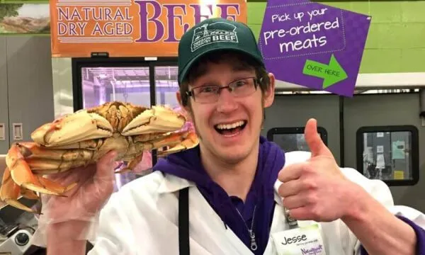 A smiling Newport Avenue Market employee behind the counter