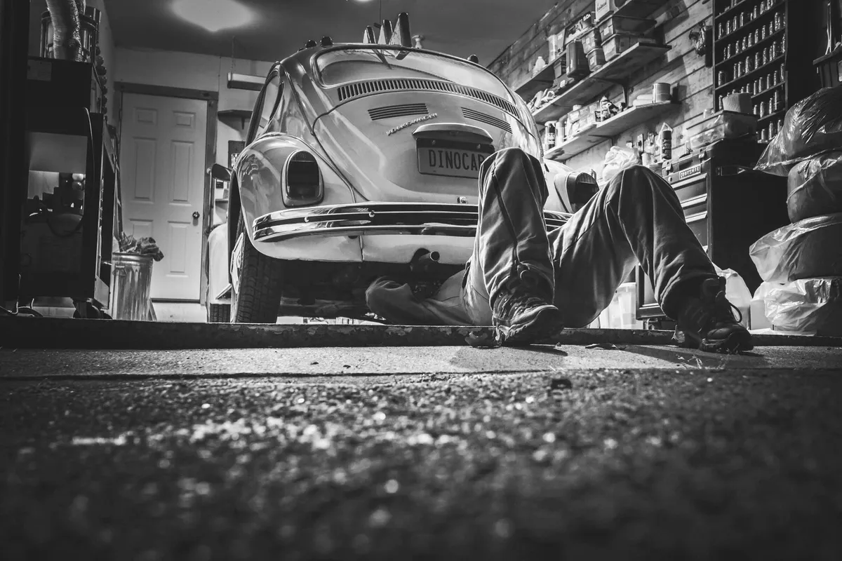 Black and white photo of a mechanic working on a car