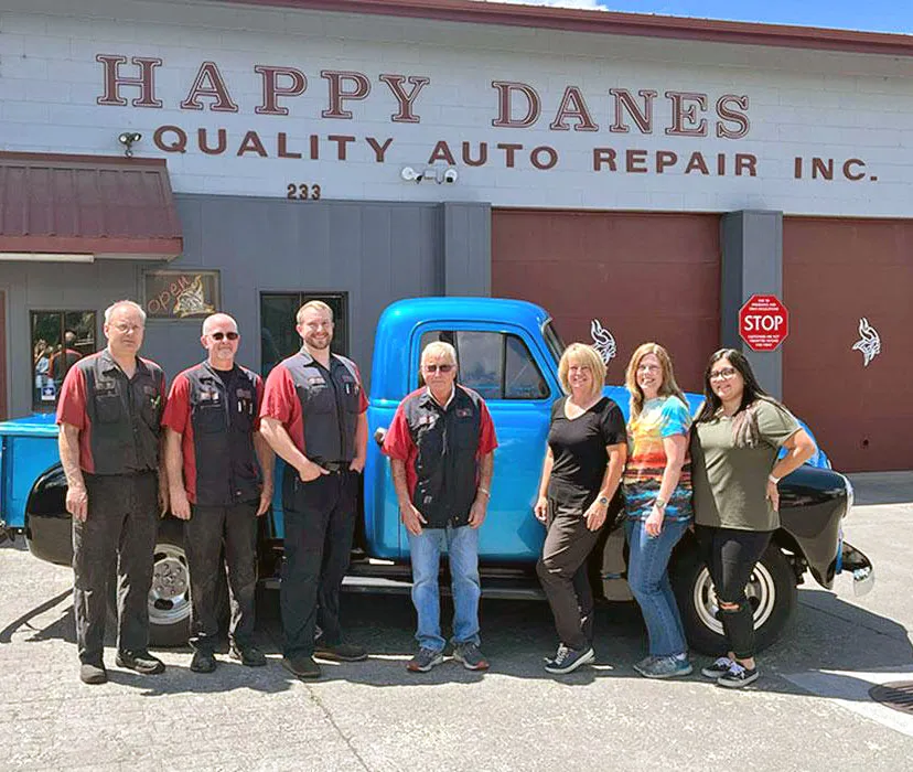 The Happy Danes Auto Repair team in front of their Bend shop with a vintage blue truck
