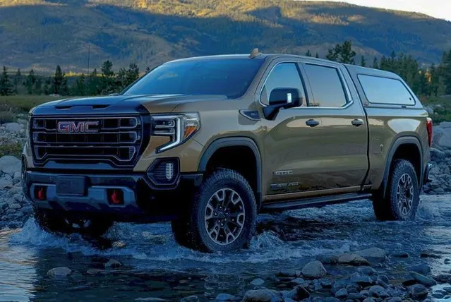 A GMC pickup driving through a river