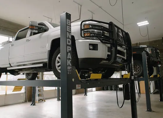 A white pickup on a lift inside Pure Auto Works in Bend