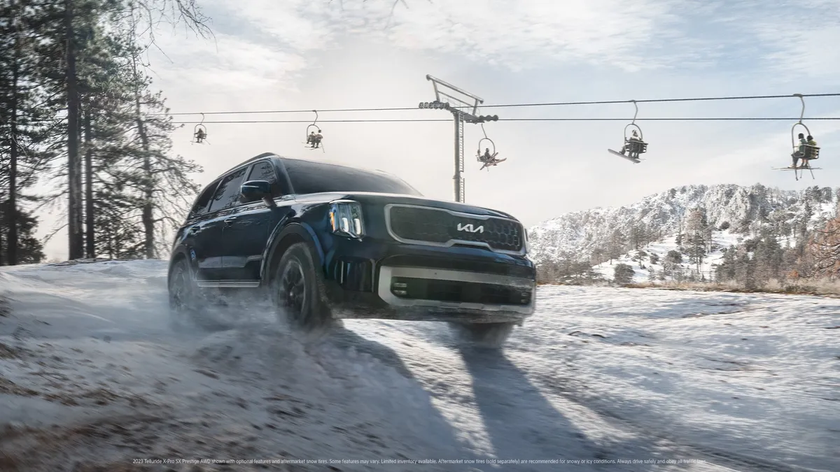 An SUV driving through snow in front of a ski lift
