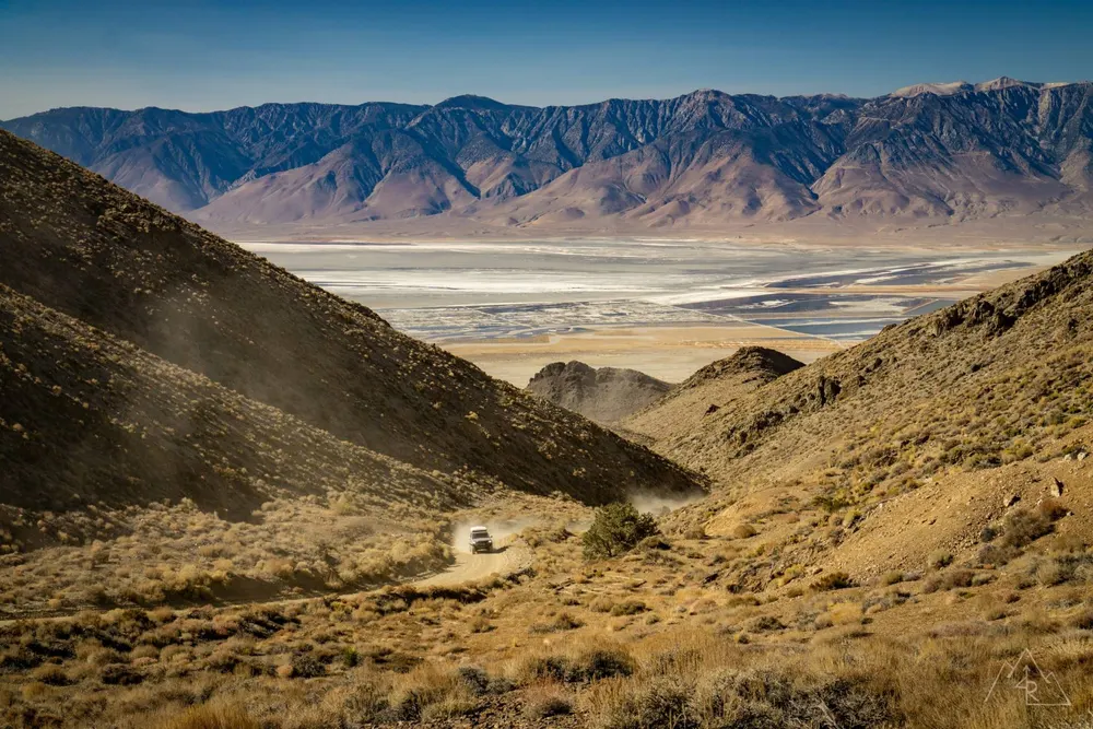 A Toyota driving a dirt road through high desert hills