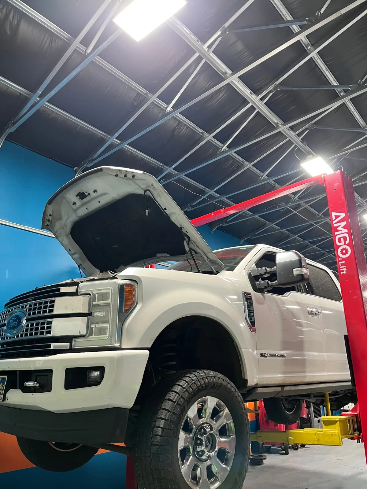 A white diesel pickup on a lift at True North Automotive
