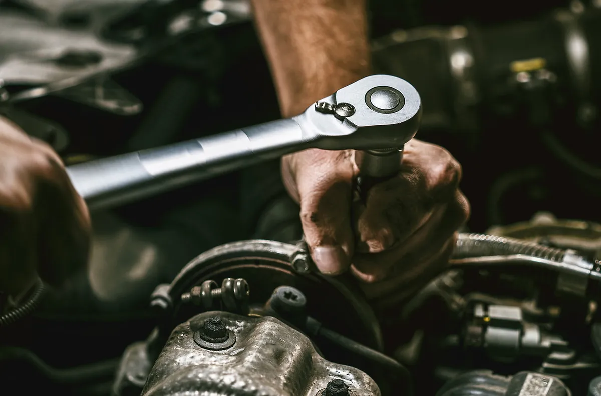 A mechanic using a wrench on an engine