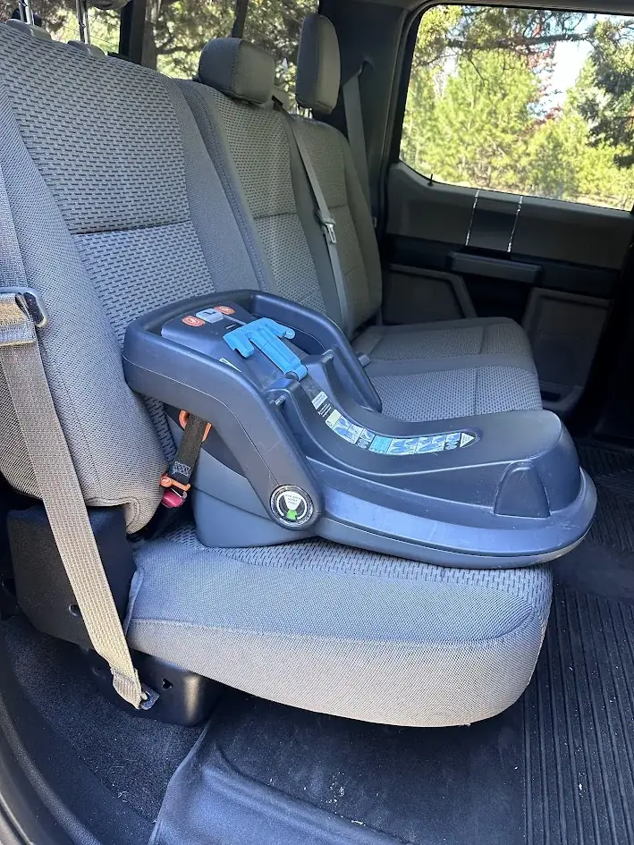 Side view of an infant car seat base buckled into the rear seat of a crew cab pickup in Central Oregon
