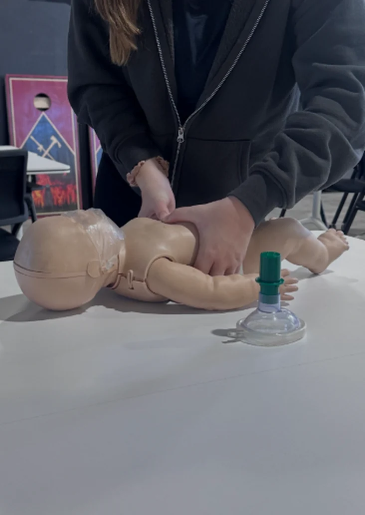 Parent practicing chest compressions on an infant training manikin at a CPR class in Bend, Oregon