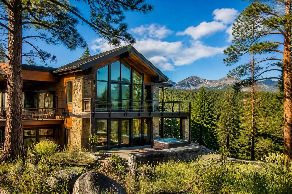 A glass-walled mountain home with a deck, from Basecamp Vacation Rentals