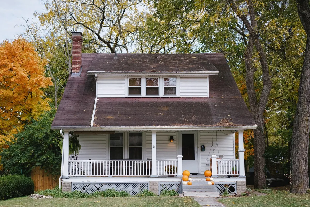 A white farmhouse-style rental home with fall trees, from Property Leaders