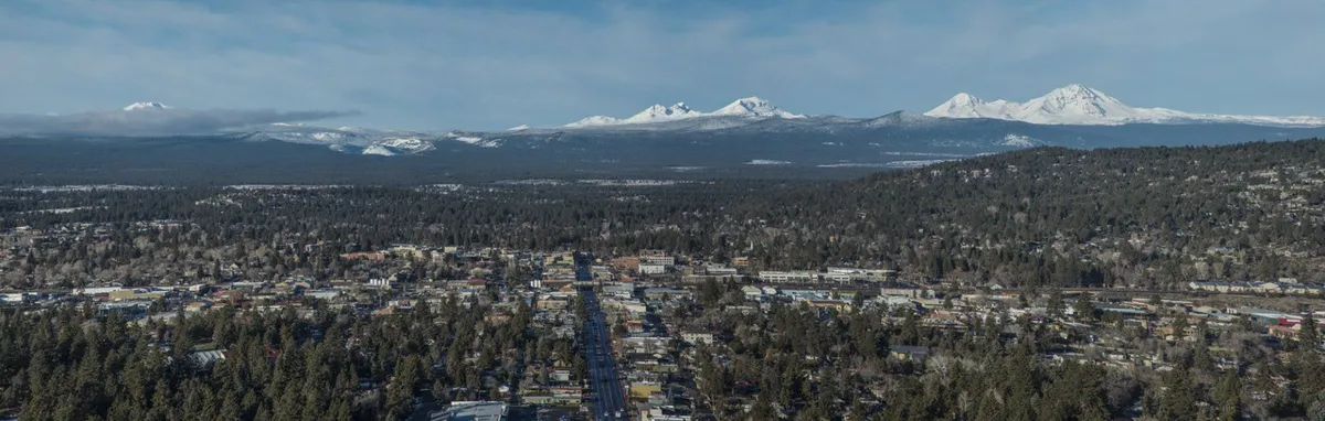 Aerial view of Bend with the Cascade peaks on the horizon, from Lifestyles Realty Group