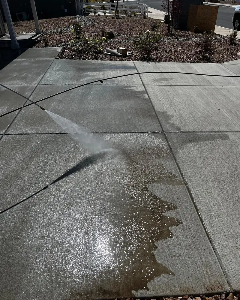 Wet concrete patio mid-wash with the clean section clearly lighter