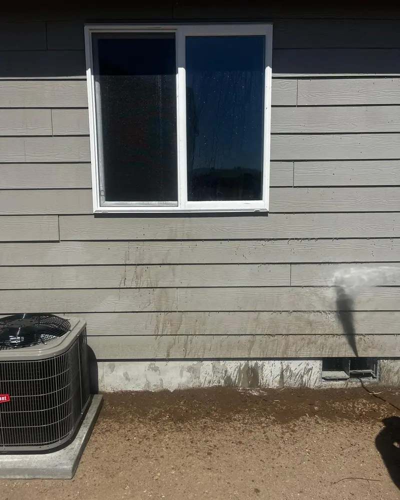 Low-pressure rinse on gray lap siding beside an air conditioner