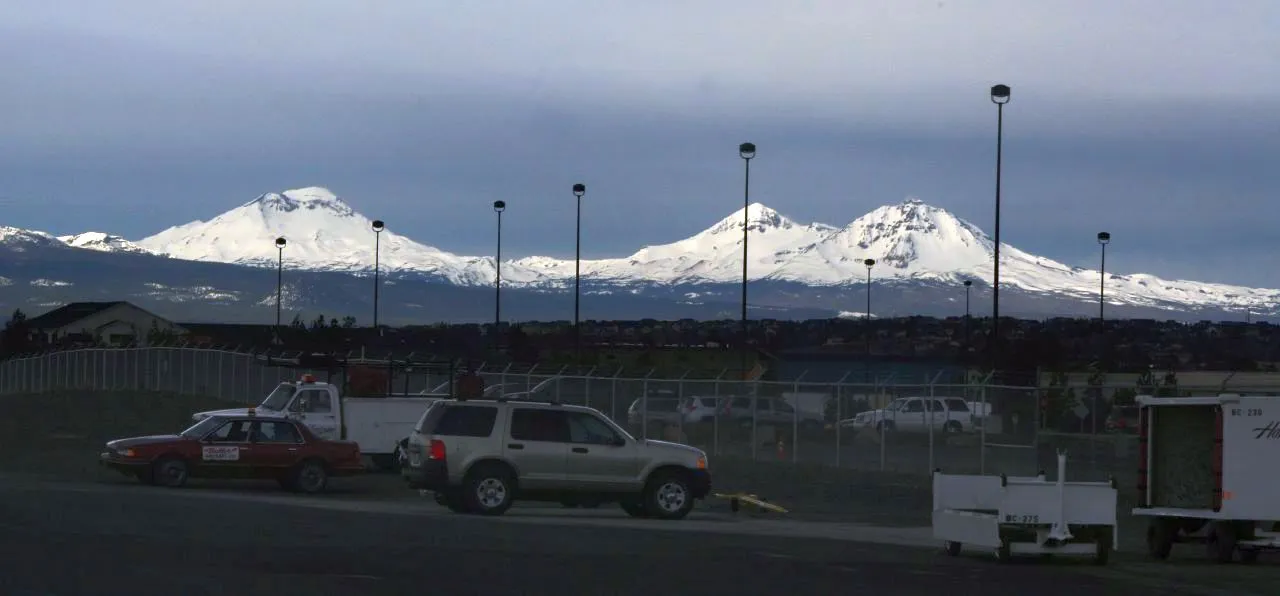 The snowy Three Sisters peaks seen across the parking area at Redmond Airport (RDM)