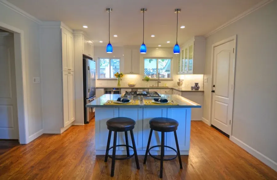 Kitchen with a blue island and pendant lights by Bend Residential Solutions