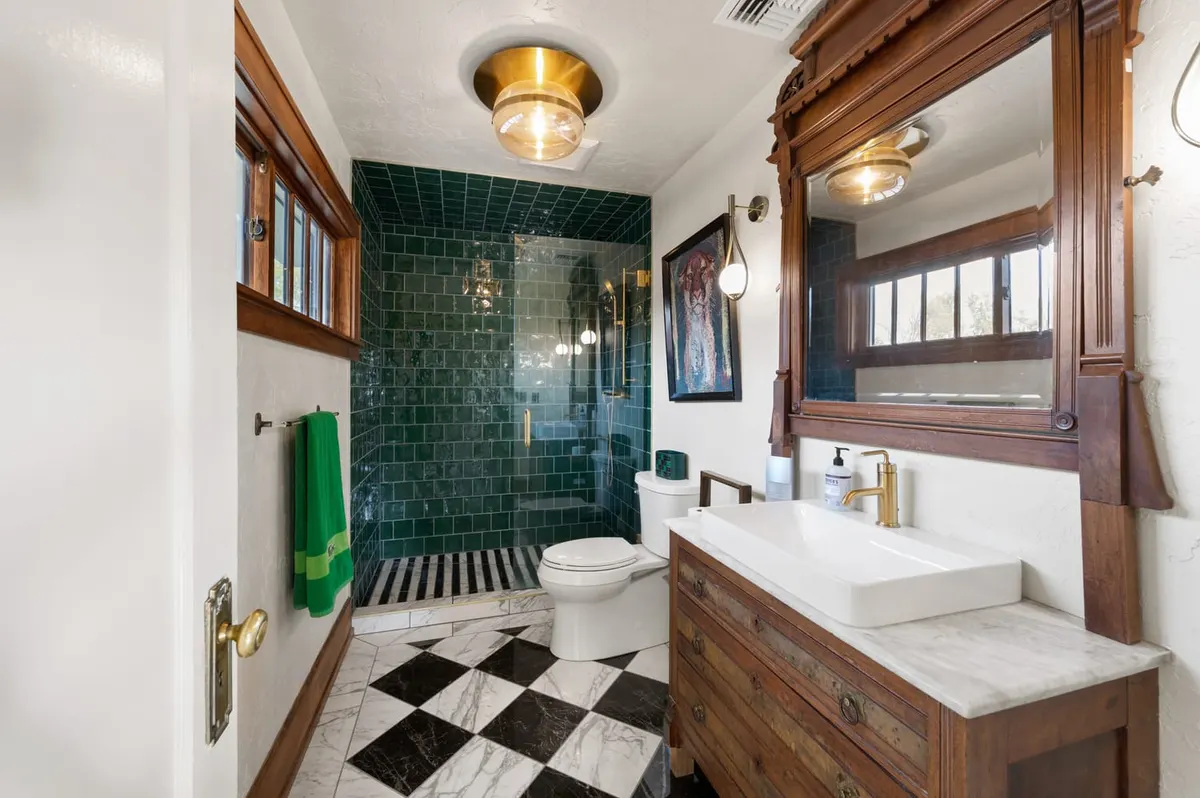 Bathroom with green tile shower, checkerboard floor and a wood vanity by Branch Brothers