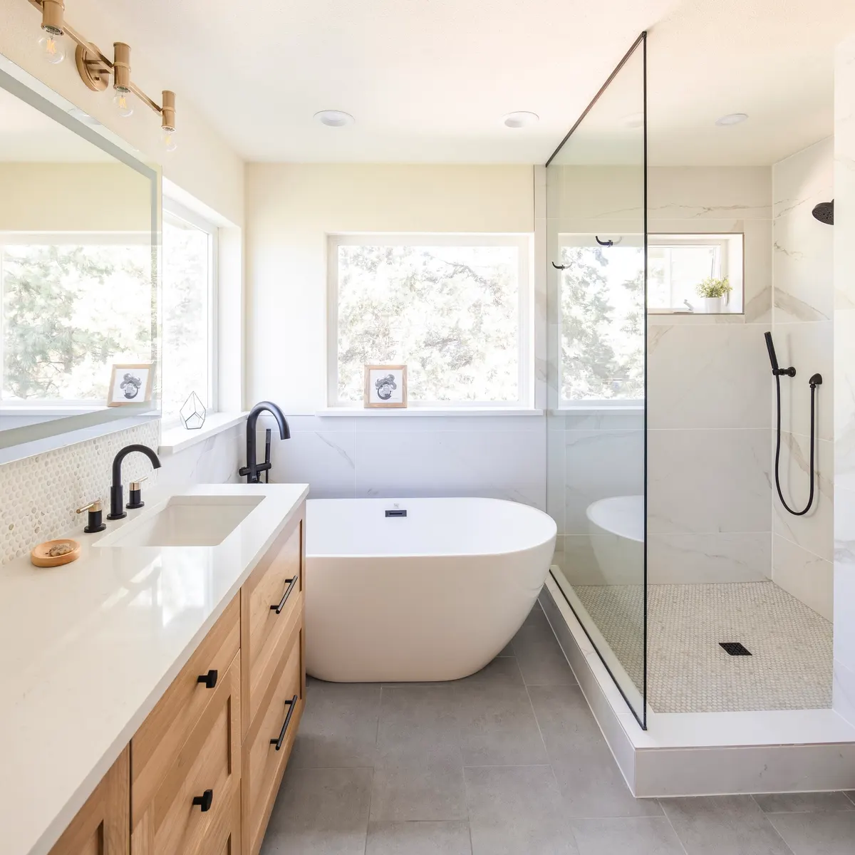 Primary bath with a freestanding tub, wood vanity and glass shower by DCR Northwest