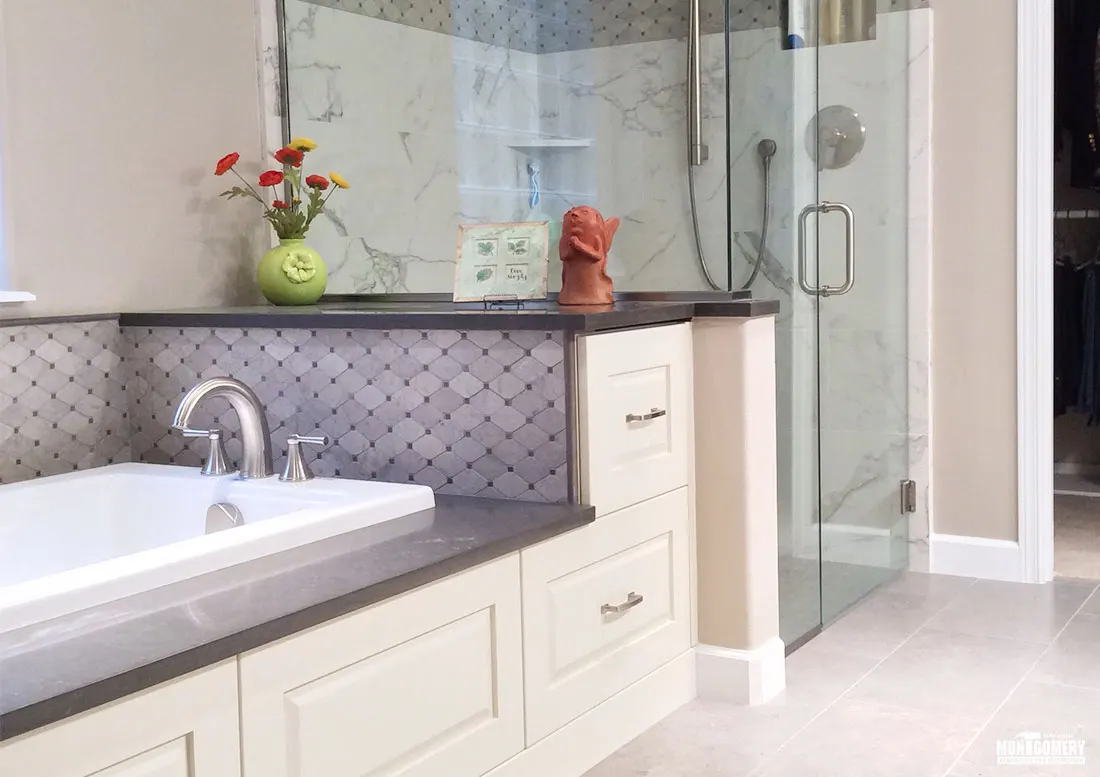 Bathroom with a drop-in tub, glass shower and cream cabinets by Montgomery Remodeling and Restoration