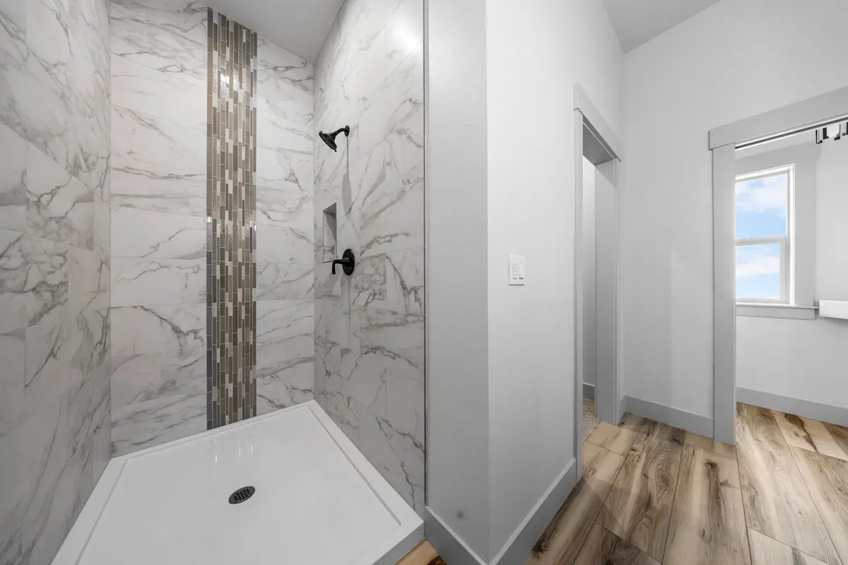 Marble-look tile shower with a mosaic stripe by WELBuilt