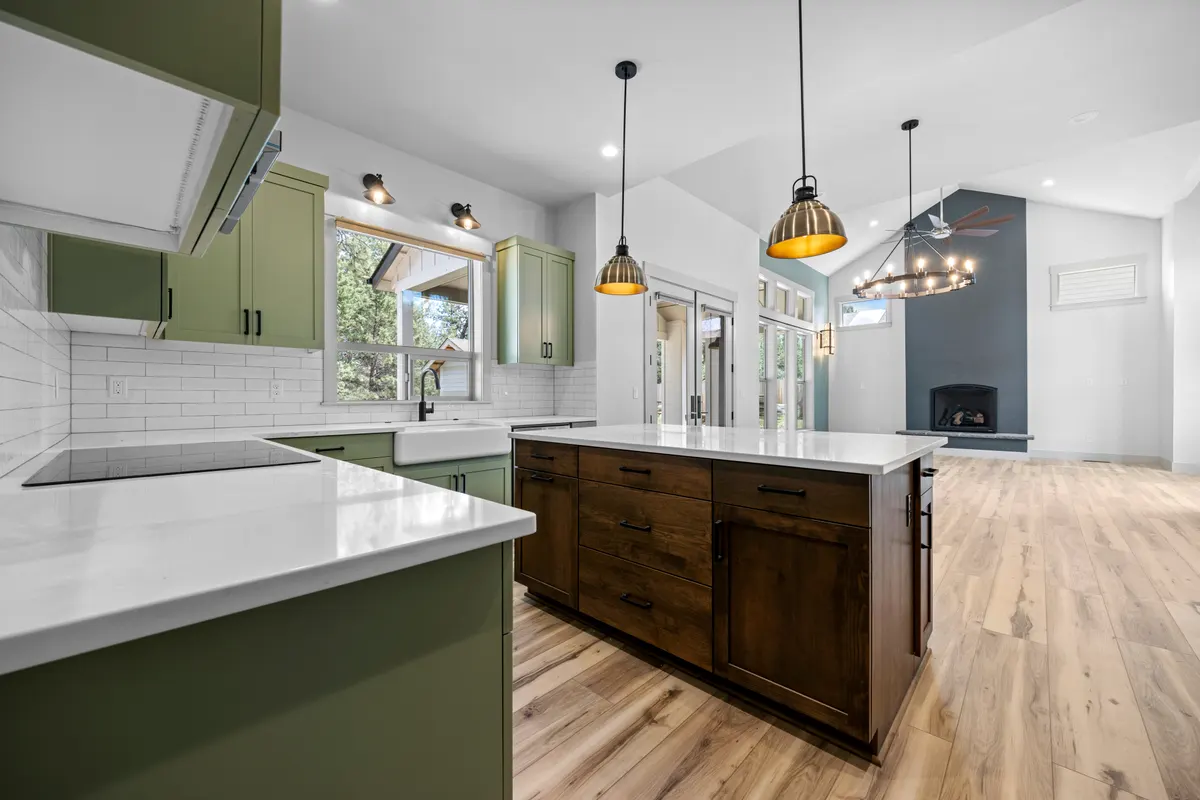 Open kitchen with sage green cabinets and a walnut island by WELBuilt