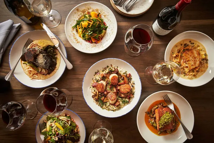 Plates of pasta, scallops and salad with red wine at Amaterra Kitchen + Social Club in downtown Bend