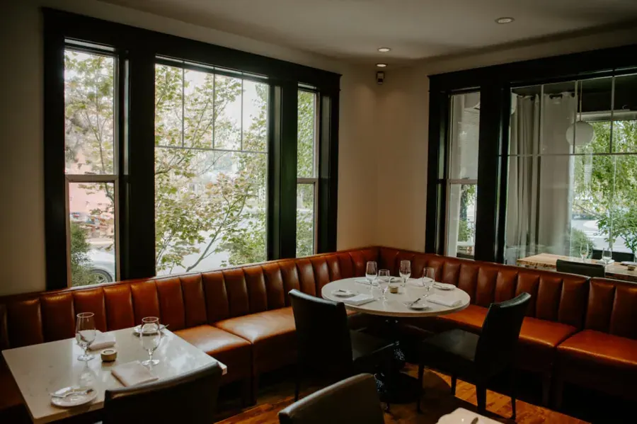 The dining room with a leather banquette and big windows at Ariana Restaurant on Galveston in Bend