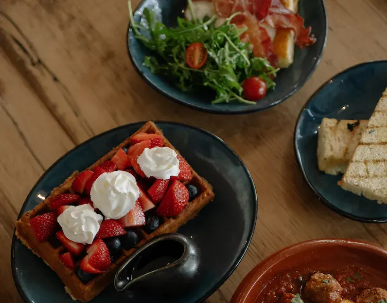 A berry waffle and brunch plates on a table at Blissful Spoon in Bend
