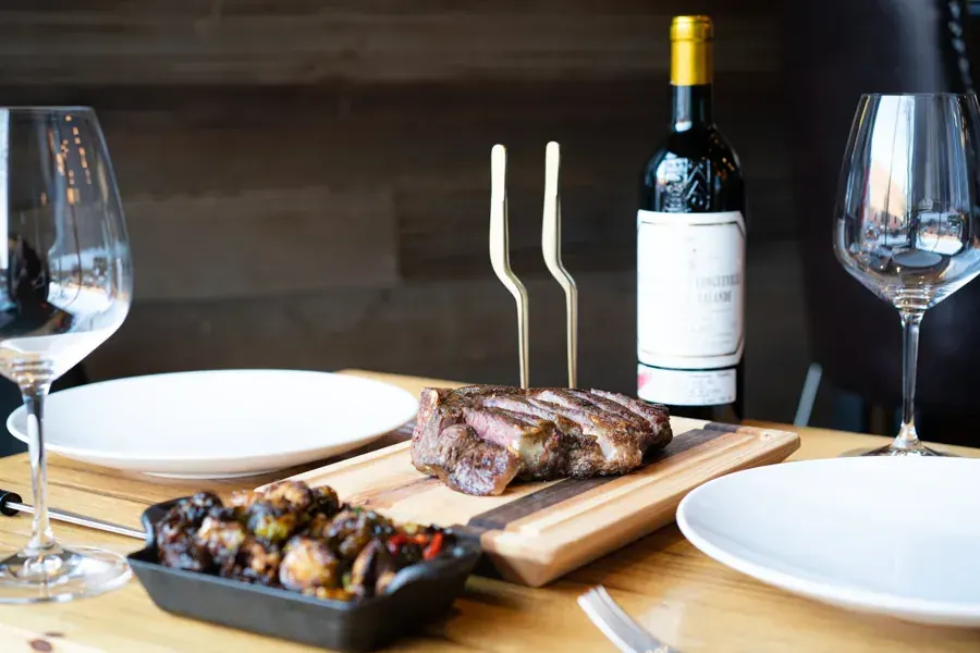 Sliced steak, roasted vegetables and a bottle of red wine at Bos Taurus steakhouse in downtown Bend