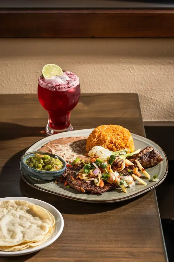A plate of grilled meat, rice and tortillas with a red cocktail at Casa Sur on Century Drive in Bend