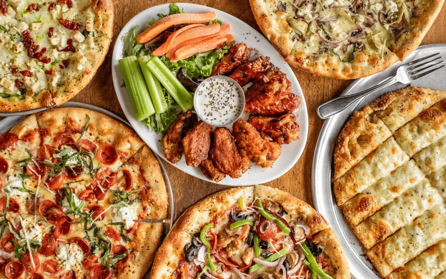 Pizzas, wings and breadsticks on a table at Little Pizza Paradise in Bend