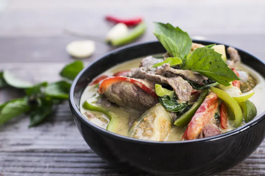 A Noi Thai curry with herbs in a dark bowl