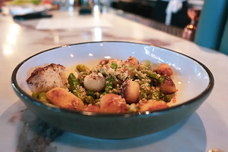 A bowl of scallops and vegetables on the marble bar at Olive & May in downtown Bend