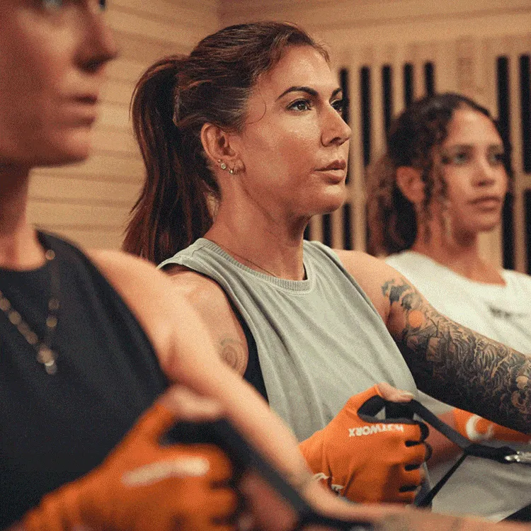 Women cycling inside an infrared sauna at HOTWORX