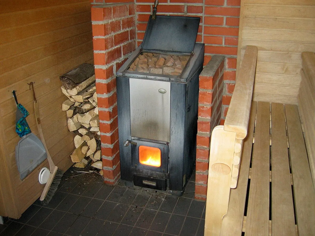 A wood-burning sauna stove with a stone basket