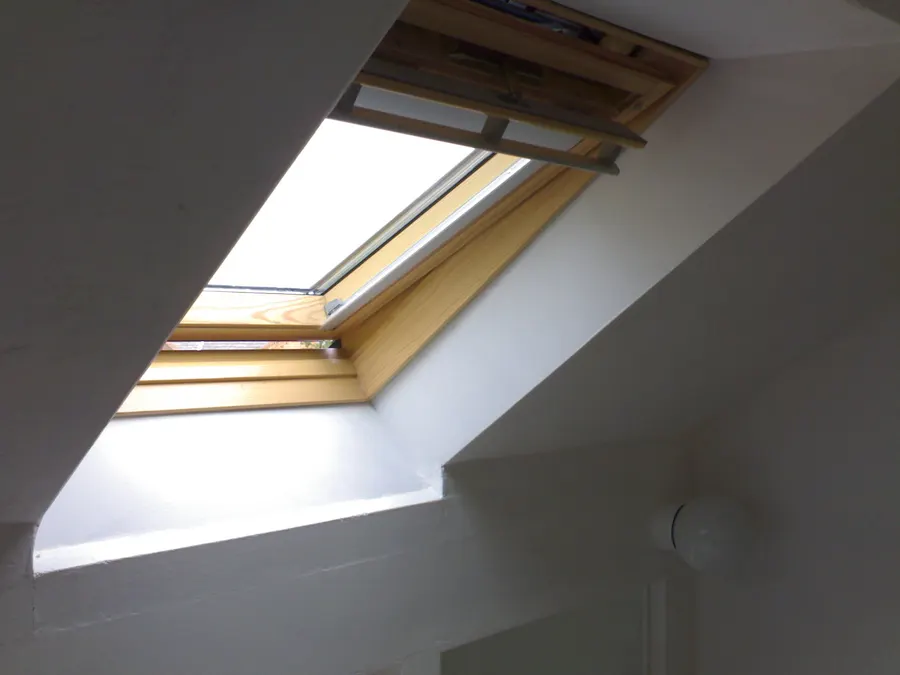 A VELUX roof window with an open blind in a sloped attic ceiling