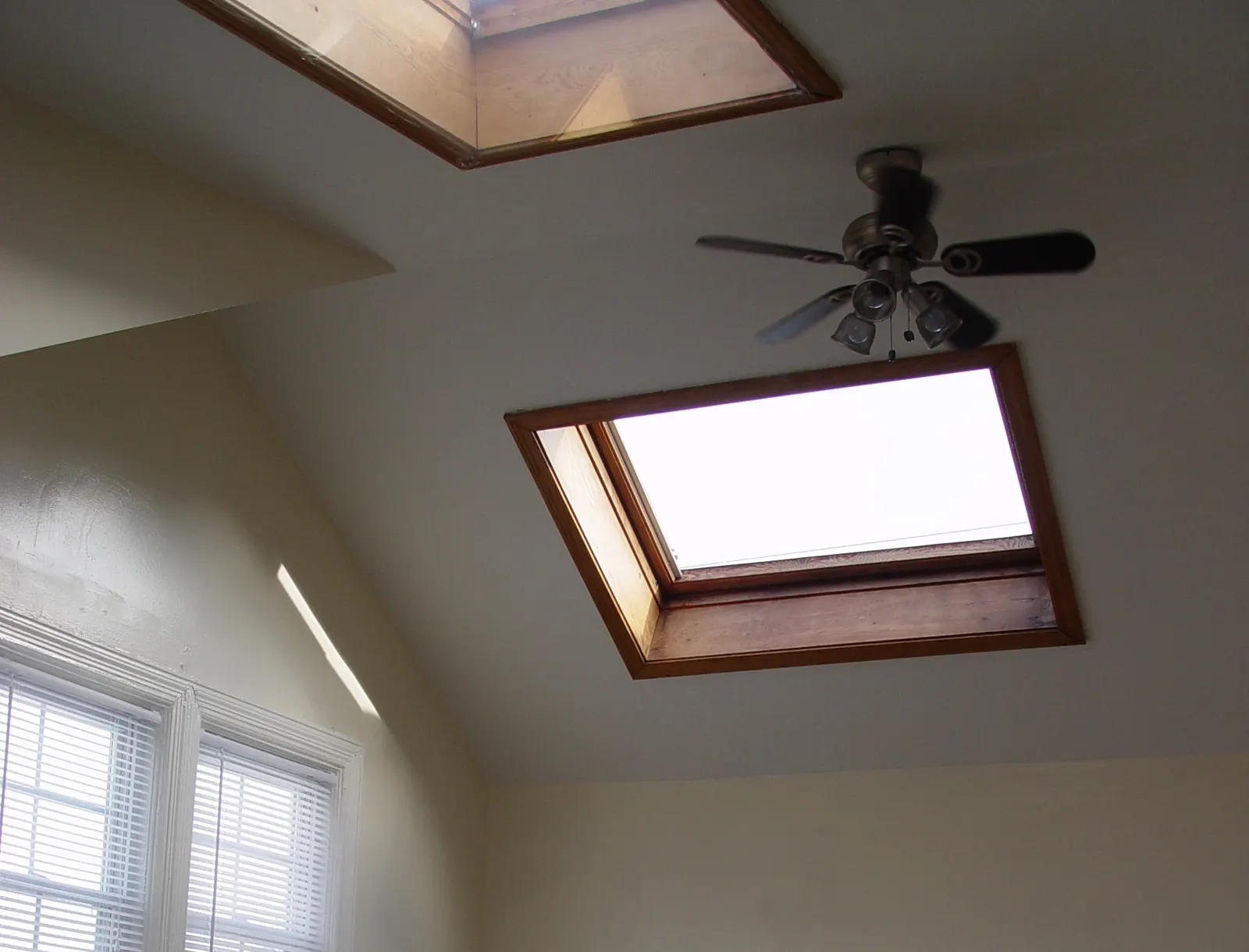A VELUX center-pivot roof window in a sloped white ceiling, letting daylight into a room
