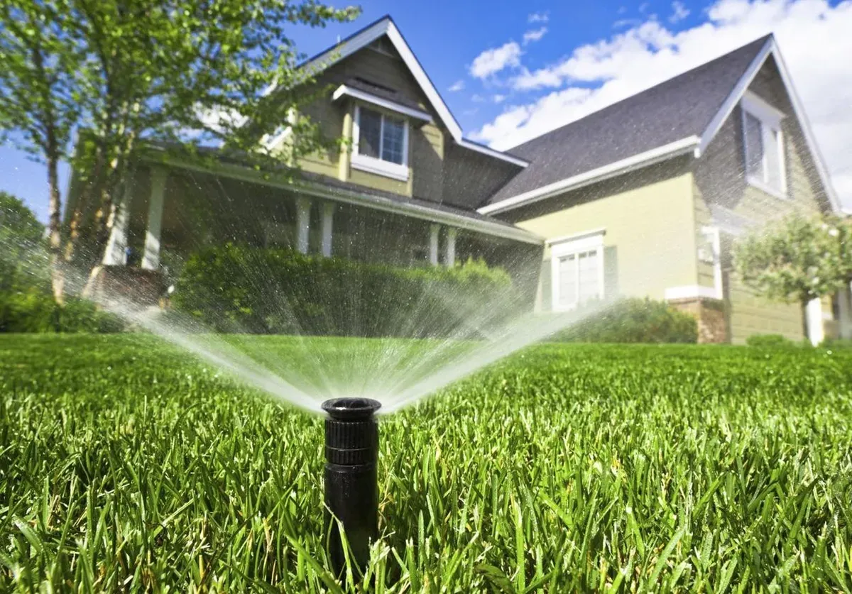 A sprinkler spraying a lawn in front of a house