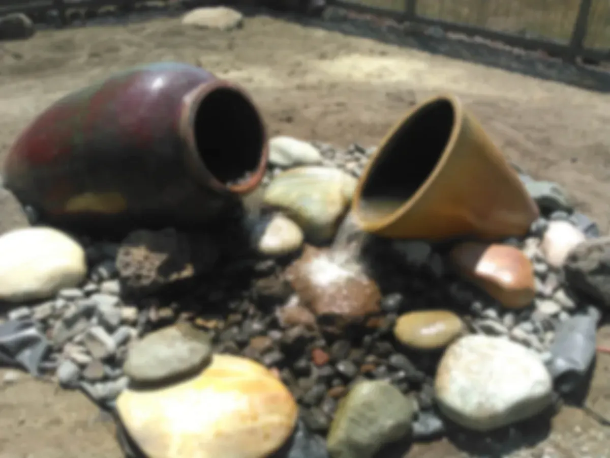Clay pots and river rock in a landscaped bed