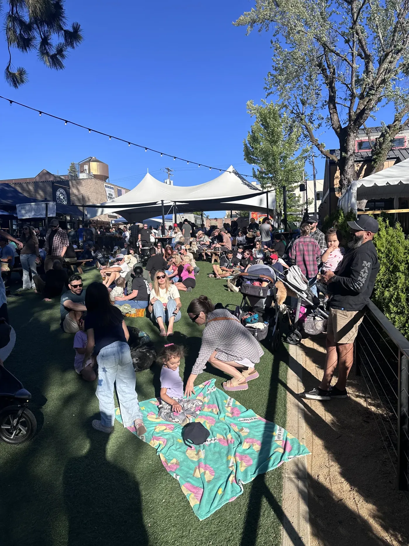 A crowded outdoor beer garden on a sunny summer evening in Bend